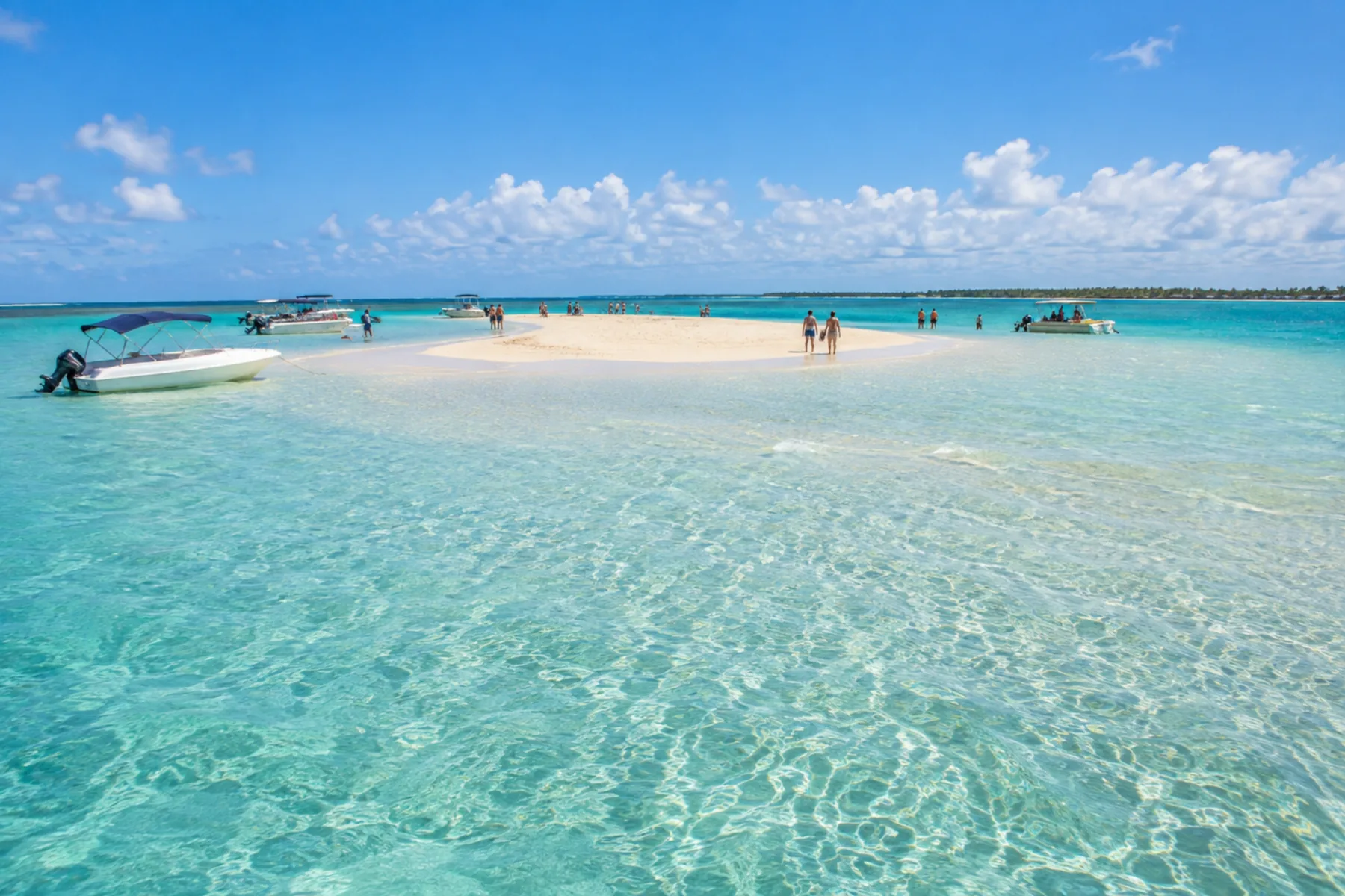 Banco de areia branca emergindo no meio do mar azul.