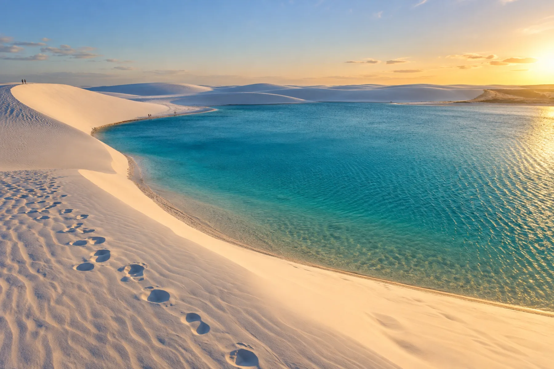 Água azul-turquesa e pegadas na areia ao redor da Lagoa Azul.