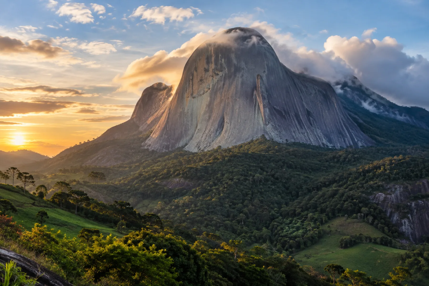 Monólito de rocha gigante com tons azulados e riscos verticais se erguendo acima de uma serra verde.