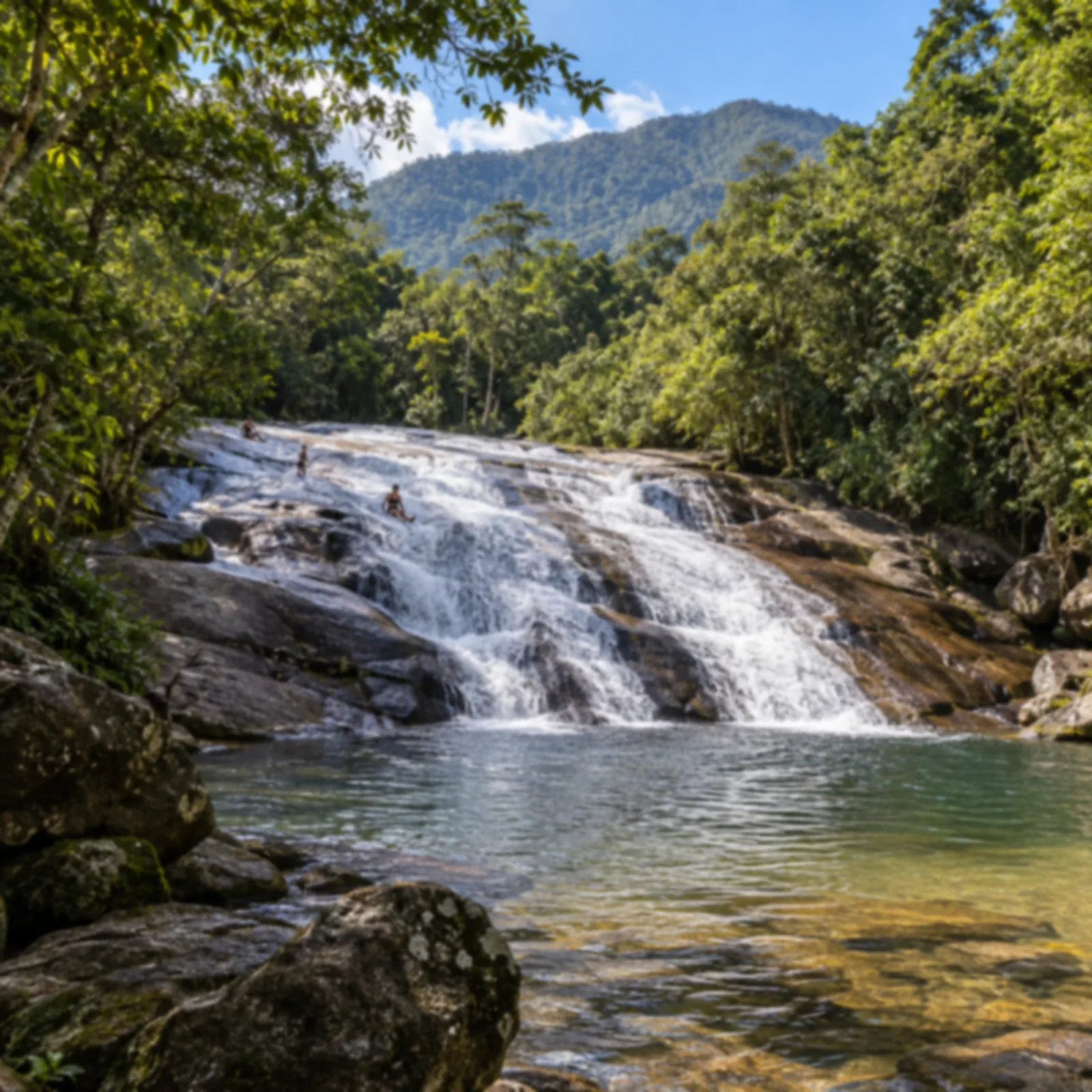 Cachoeira larga e baixa escorrendo por uma laje de pedra inclinada até um poço raso.