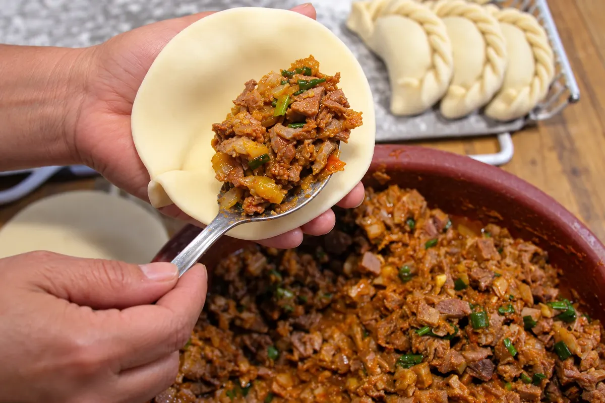 Empanada tucumana: colocação do recheio na massa.