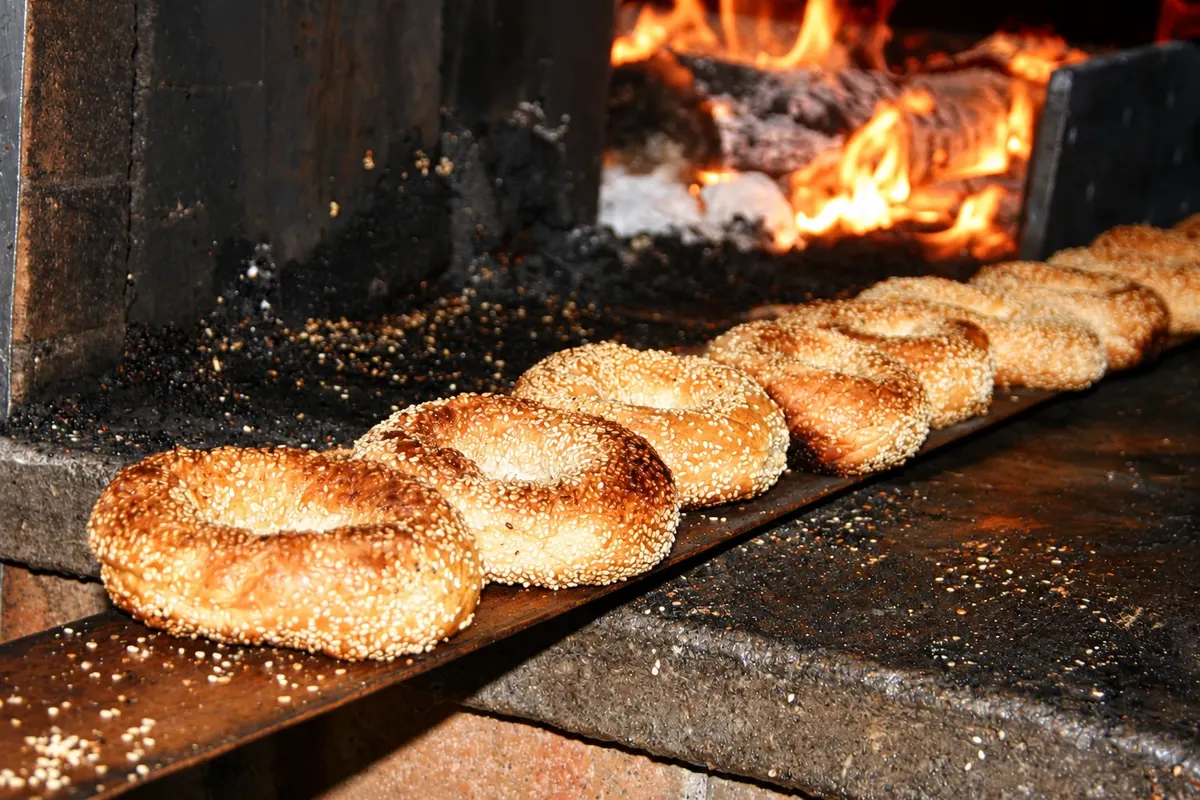 Bagels de gergelim na pá de madeira junto ao forno.